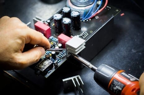 Uma pessoa está trabalhando em um componente eletrônico com uma chave de fenda.