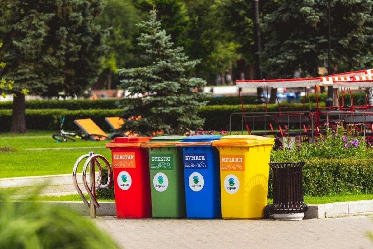 Um grupo de latas de lixo coloridas em um parque.