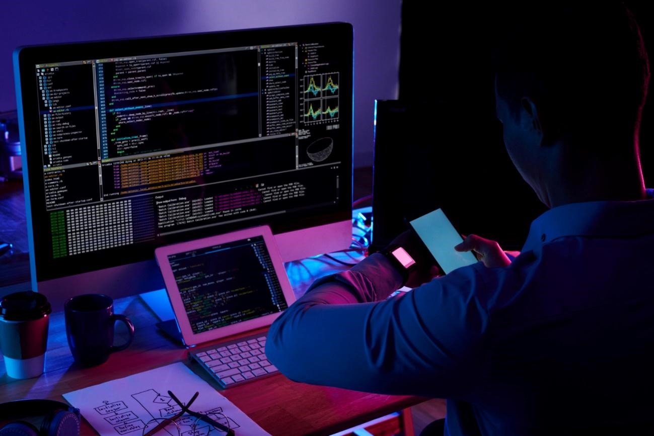 Um homem está trabalhando em um computador à noite, com foco no comportamento organizacional.