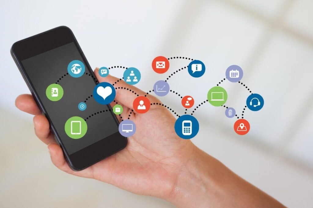 Uma mão segurando um smartphone com ícones de mídia social para desenvolver um aplicativo.
