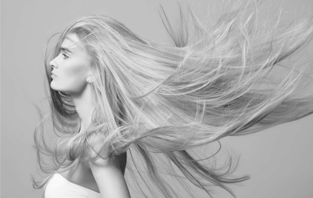 Uma foto em preto e branco de uma mulher, um case de sucesso, com os cabelos ao vento.