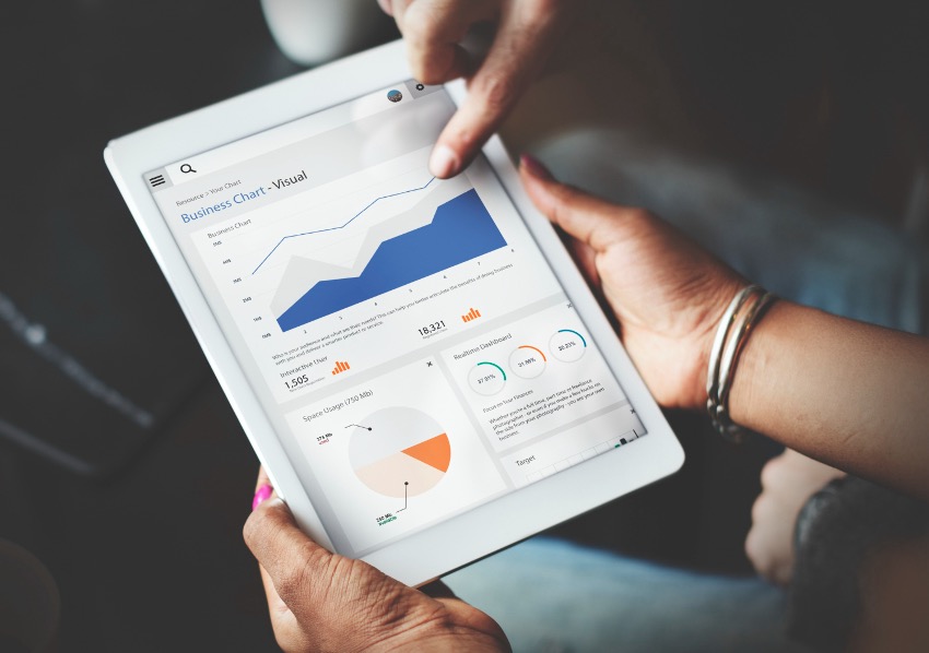 Duas pessoas analisam gráficos de negócios, incluindo gráficos de linhas e pizza, em um tablet, aproveitando a Inteligência de Dados para uma melhor Tomada de Decisões.