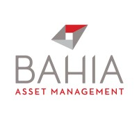 Logotipo da Bahia Asset Management com texto estilizado com um desenho geométrico vermelho e cinza acima do nome da empresa. A palavra "BAHIA" aparece em cinza, enquanto "ASSET MANAGEMENT" está escrito em vermelho, incorporando a abordagem integrativa inerente aos seus workshops abrangentes.