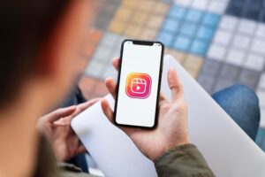 Uma pessoa segurando um smartphone com o logotipo do Instagram Reels exibido na tela, pronta para explorar as últimas tendências ou interagir com um chatbot do instagram