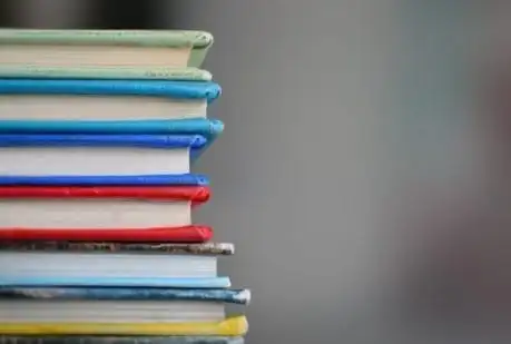 Uma pilha de livros sobre uma mesa com fundo desfocado.