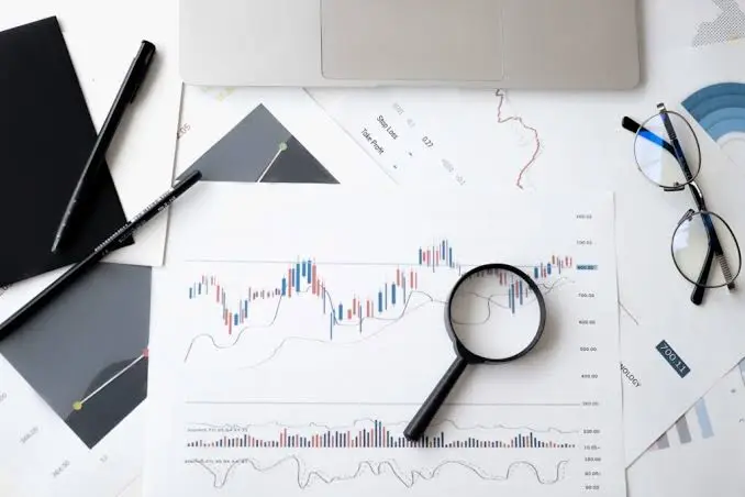Uma lupa sobre uma mesa com laptop, papel e materiais de consultoria para empresas.