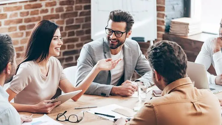 Um grupo de pessoas sentadas ao redor de uma mesa em uma reunião de consultoria para empresas.