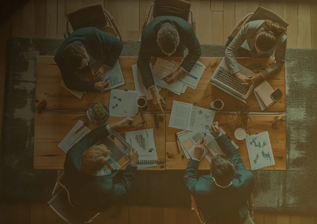 Um grupo de pessoas sentadas ao redor de uma mesa de madeira.