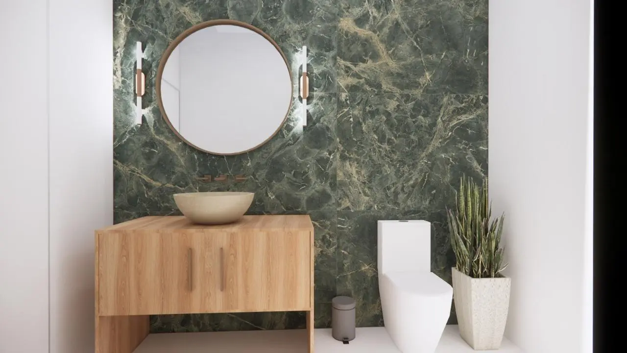 Refúgio Aurora | WhatsApp Image 2025 05 08 at 20.21.31 2 Banheiro moderno com espelho redondo, bancada de madeira com pia, vaso sanitário branco, planta em vaso e parede com detalhes em mármore verde.
